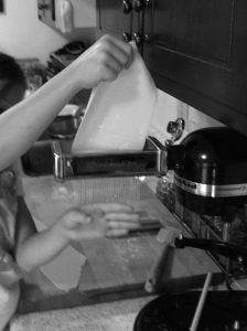 Cutting spaghetti noodles with KitchenAid pasta machine black and white photo on andreabadgley.com