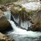Winter stream with icicles, boulders, and moss on andreabadgley.com